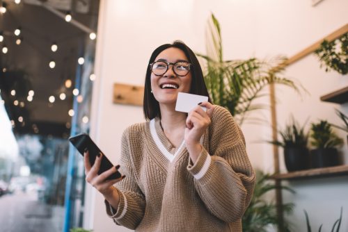 Girl with business card using smartphone in cafe